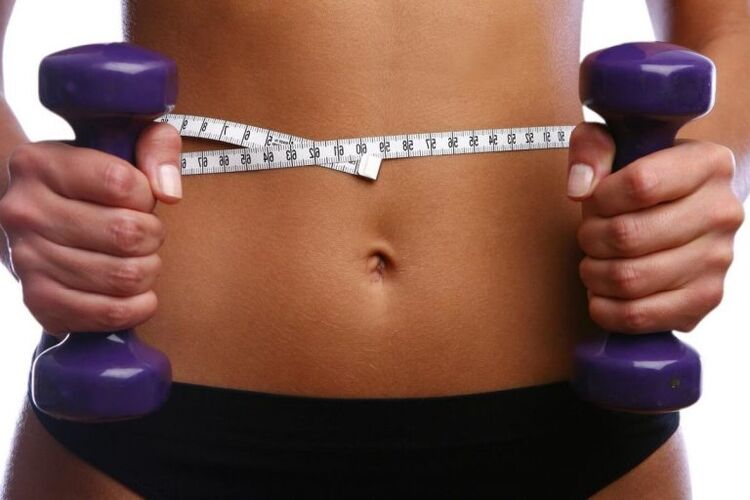 Dumbbells kecergasan di tangan seorang gadis yang sesuai